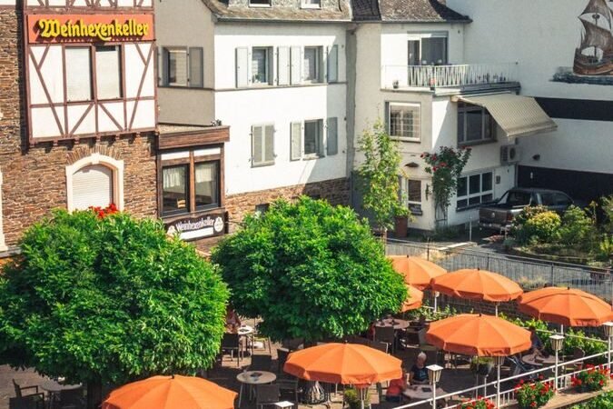 A picturesque street view of Cochem, Germany showcasing traditional architecture, a cafe, and a cyclist.